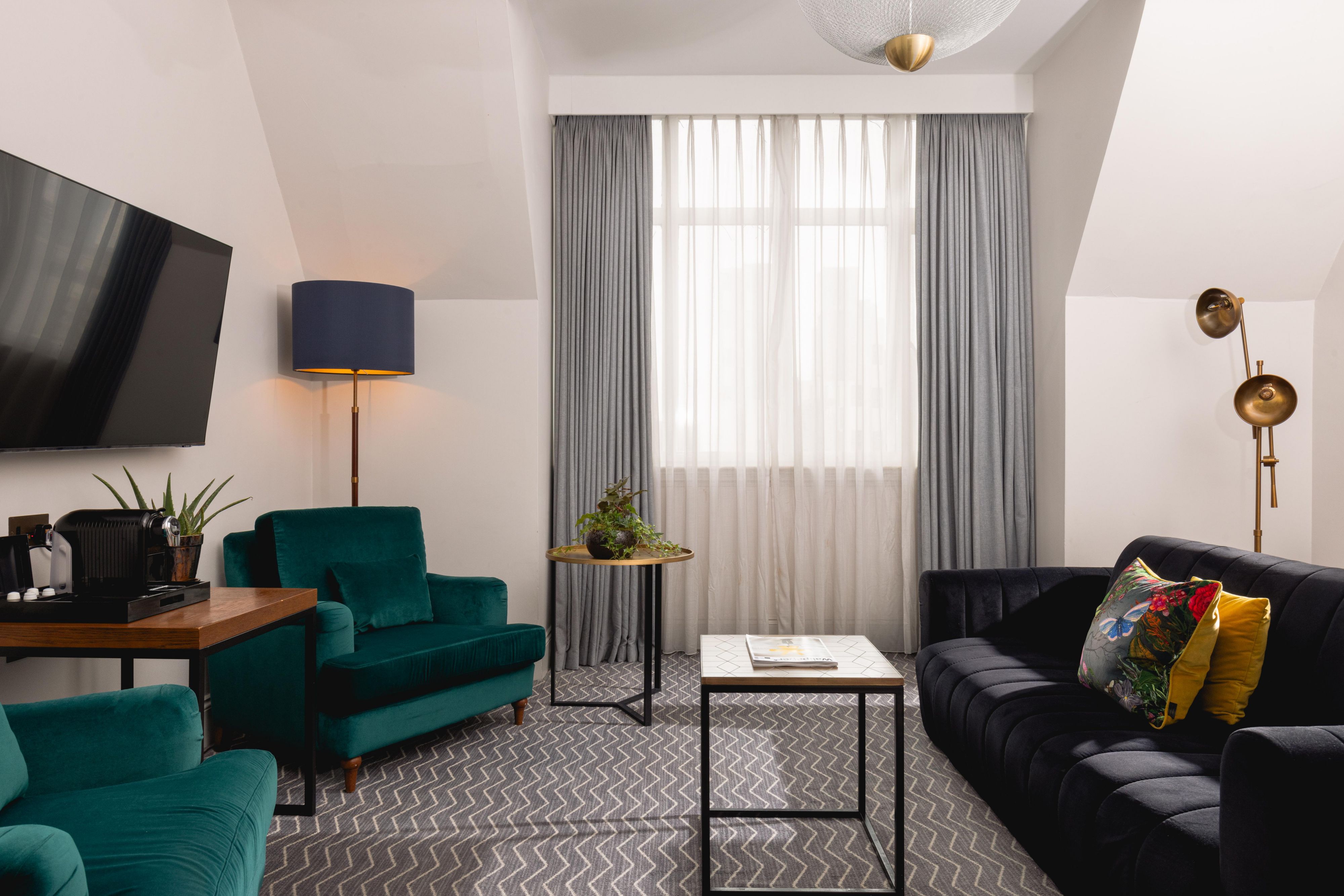 Hotel suite lounge area featuring a sofa, lounge chair, television and coffee machine