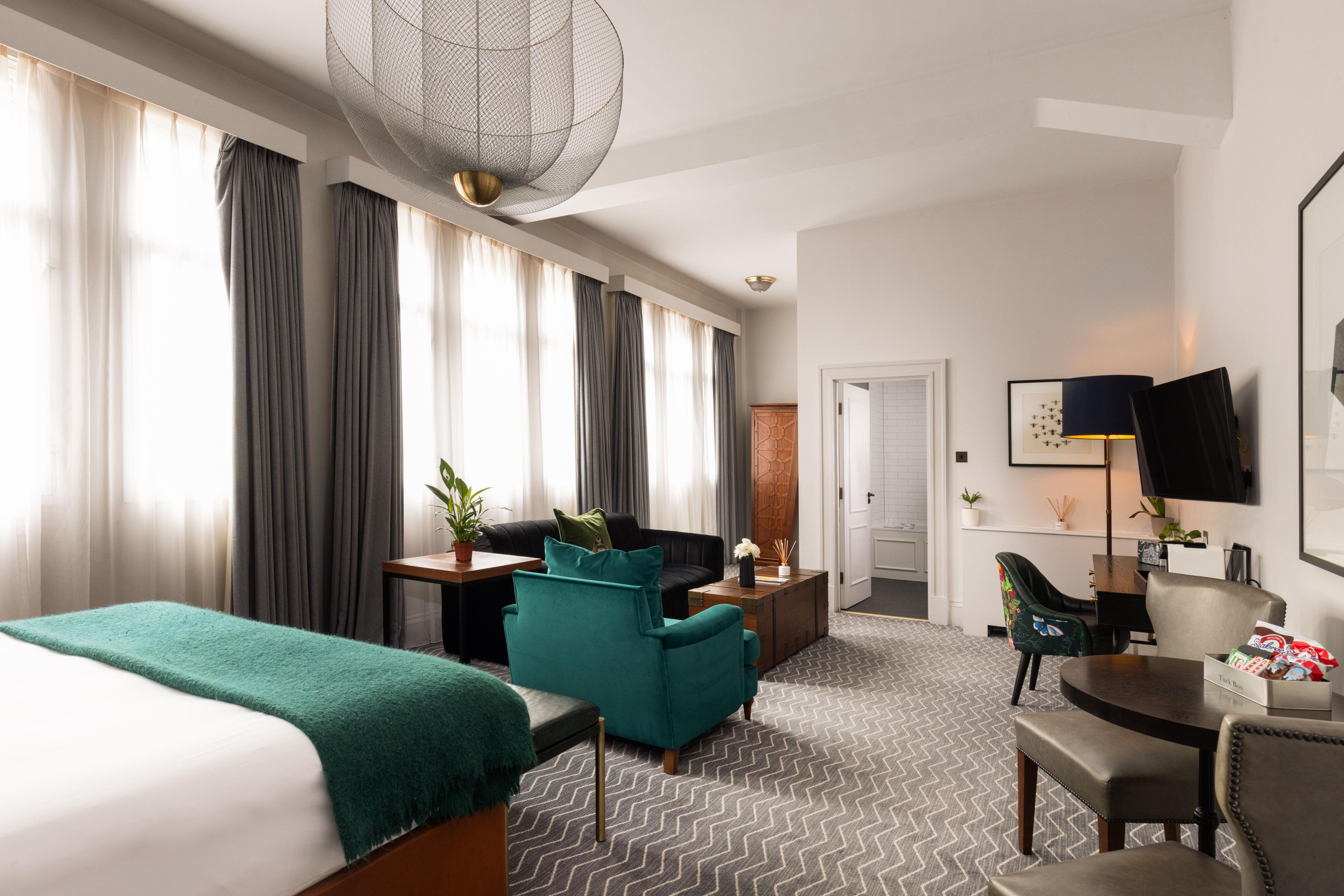 Seating area at the foot of a king-sized bed in a luxury suite