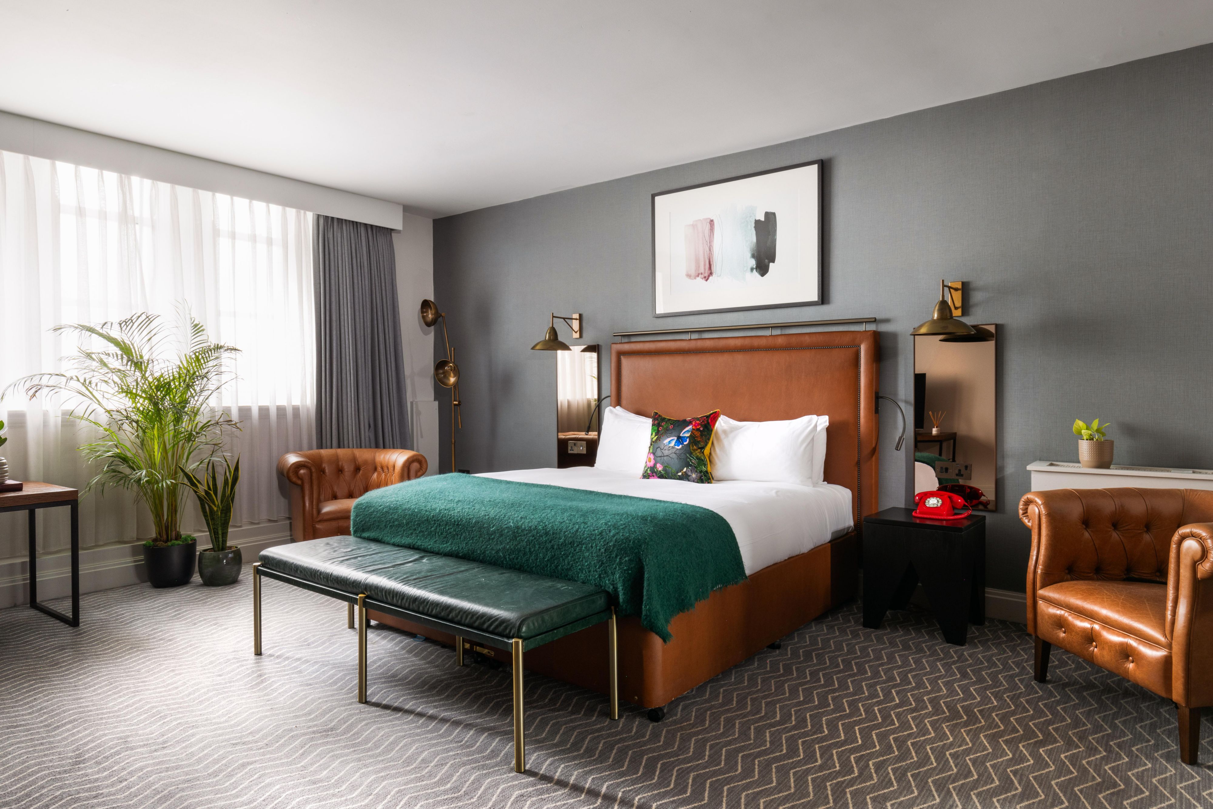 Hotel guest bedroom in a king suite, featuring king sized bed, and bedside table with a British red telephone