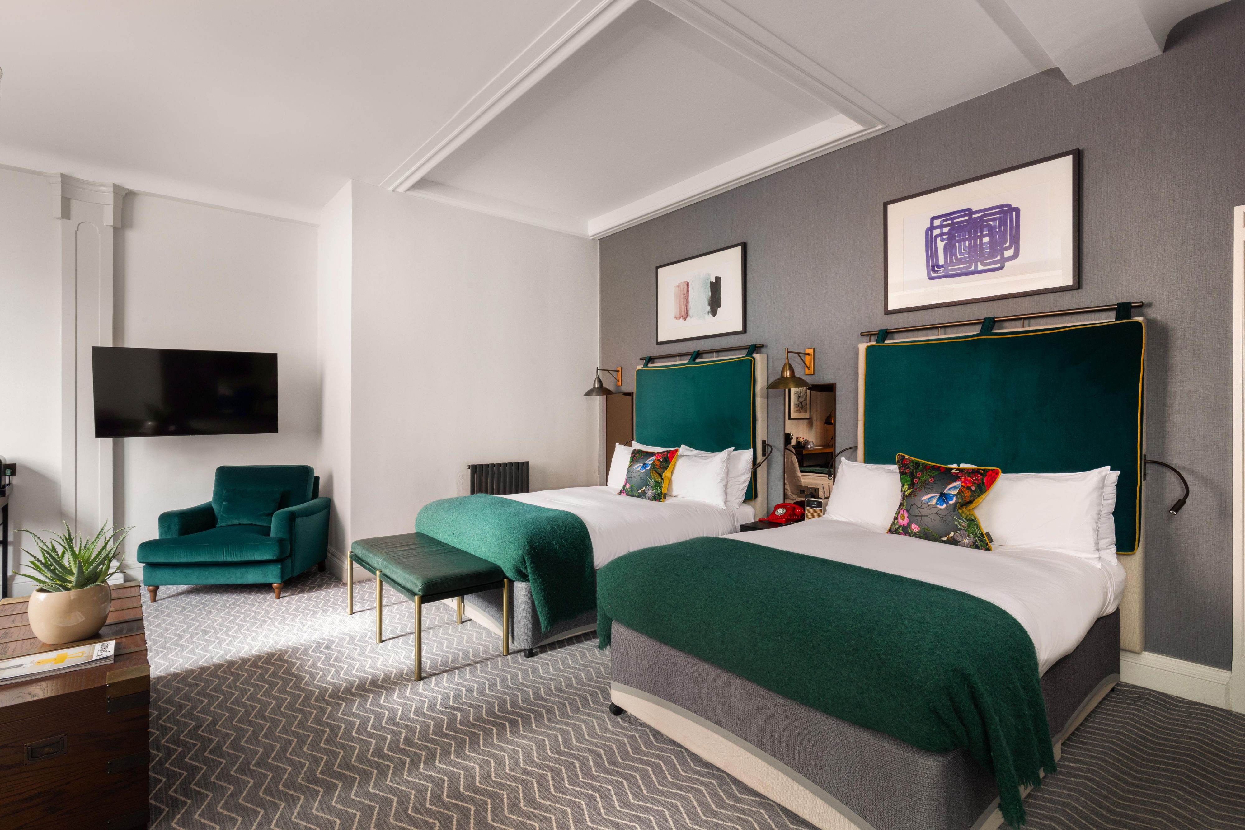 2 king sized beds in a luxury hotel suite with added television and lounge chair