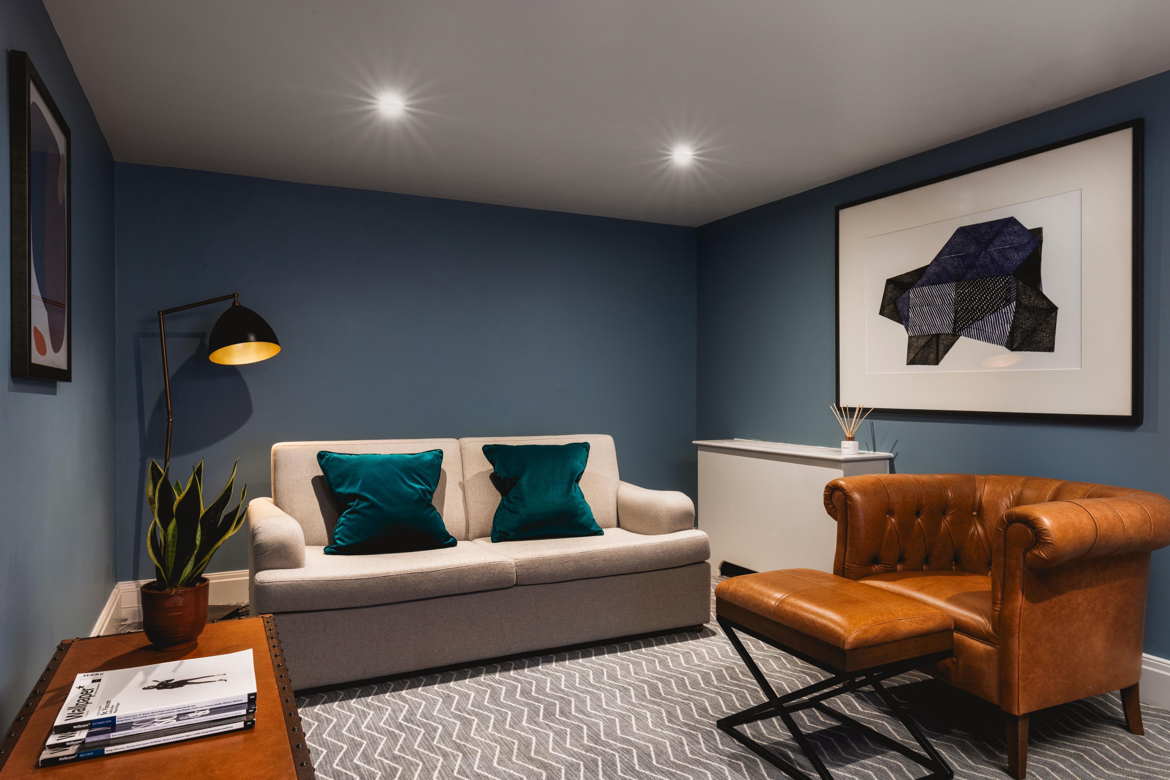 Featured lounge area in a king hotel suite with sofa, lounge chair, and artwork