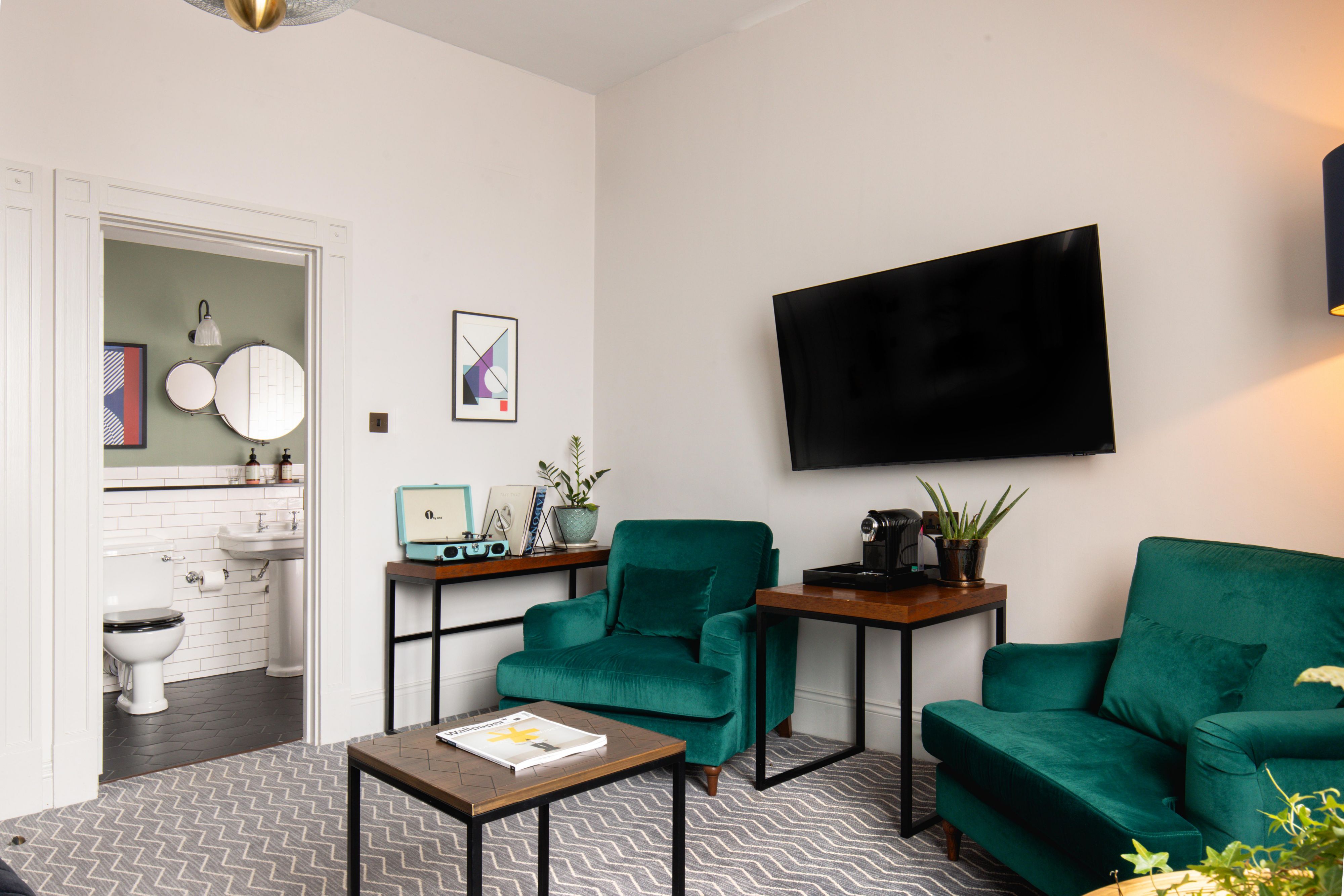 Lounge area in a king hotel suite with lounge chairs, a television and a view to the en-suite