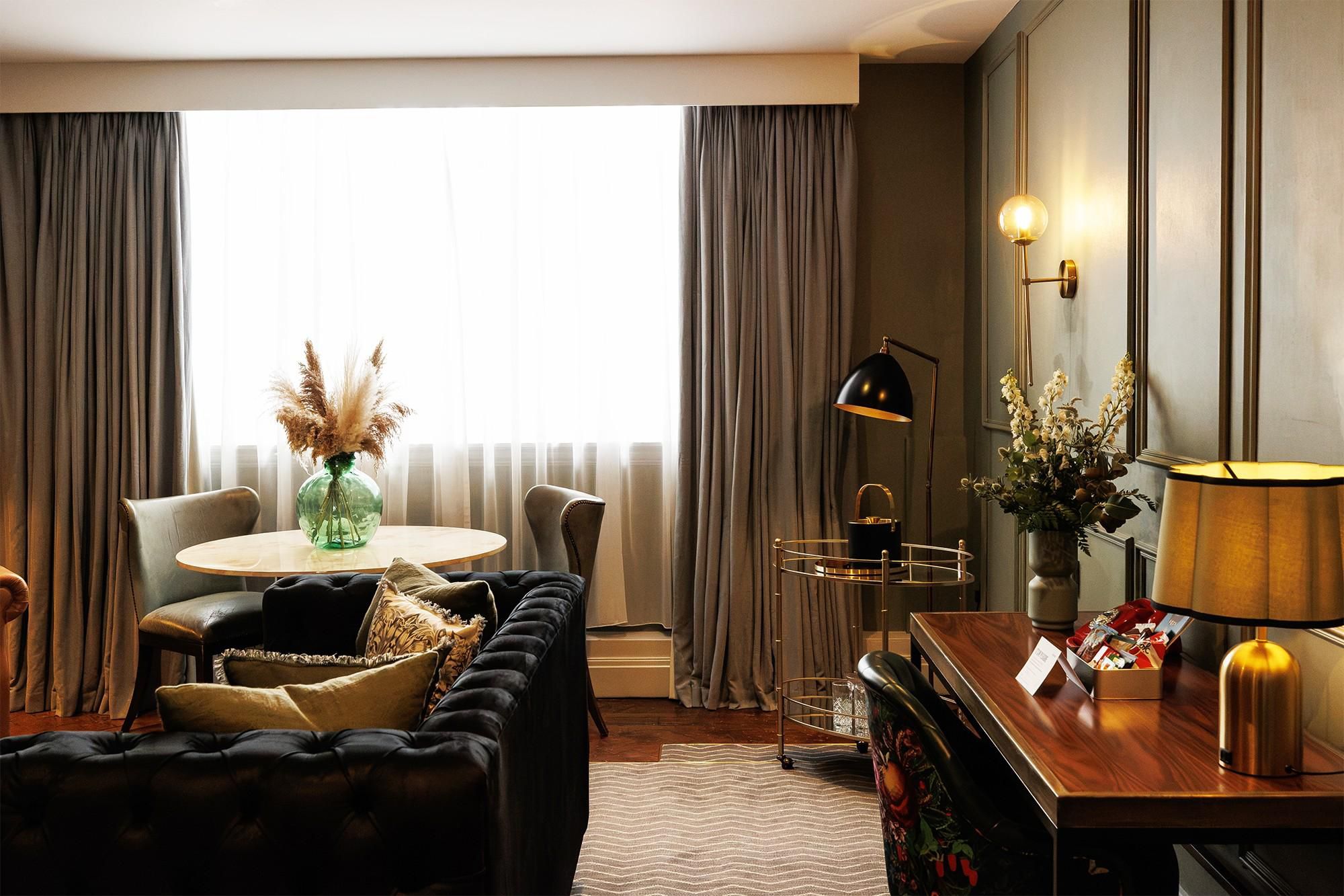 Deluxe King Suite lounge area, with sofa, working desk, and dining table