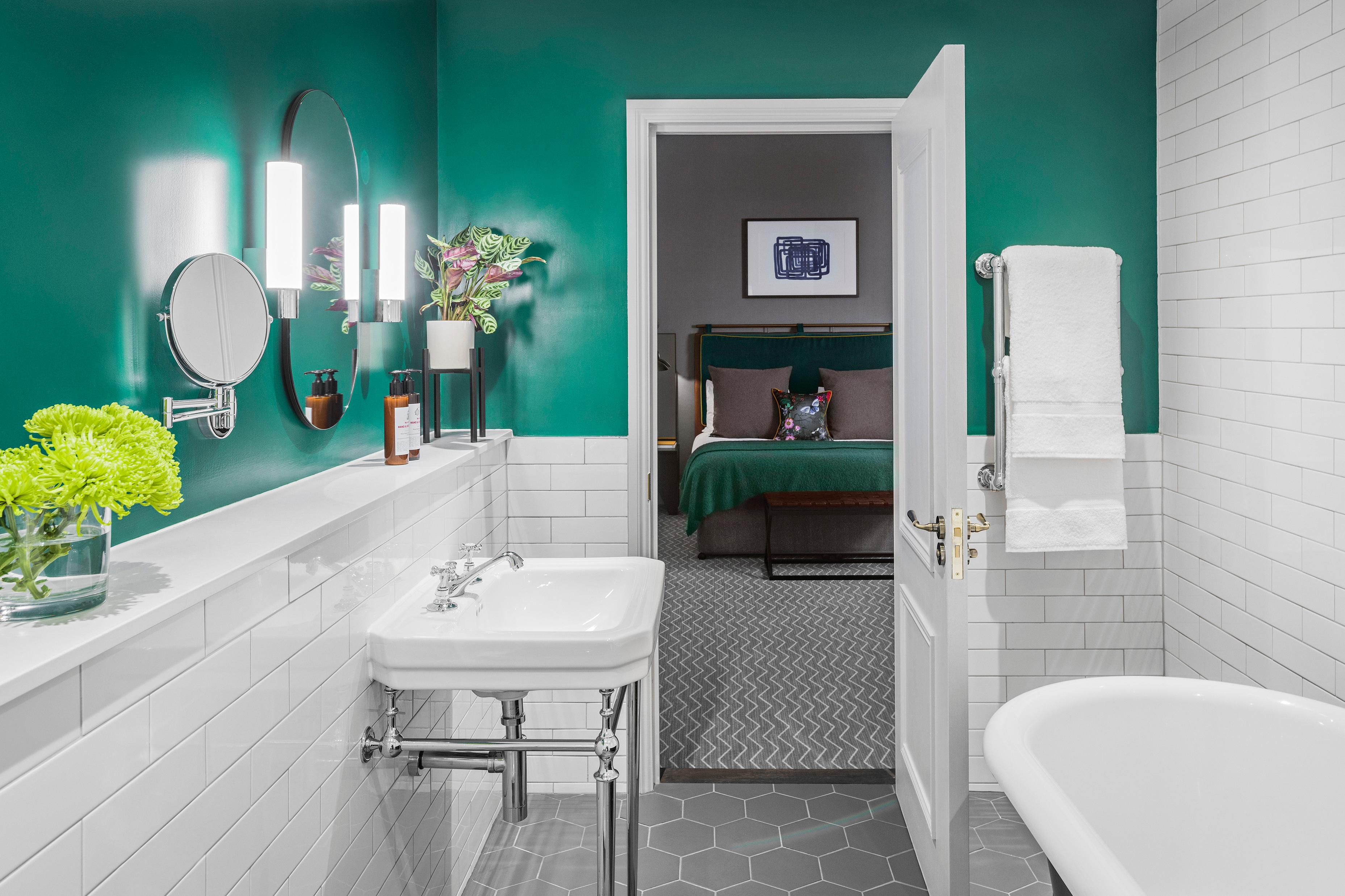 Hotel suite bathroom with sink, bath, and view into the hotel guest bedroom