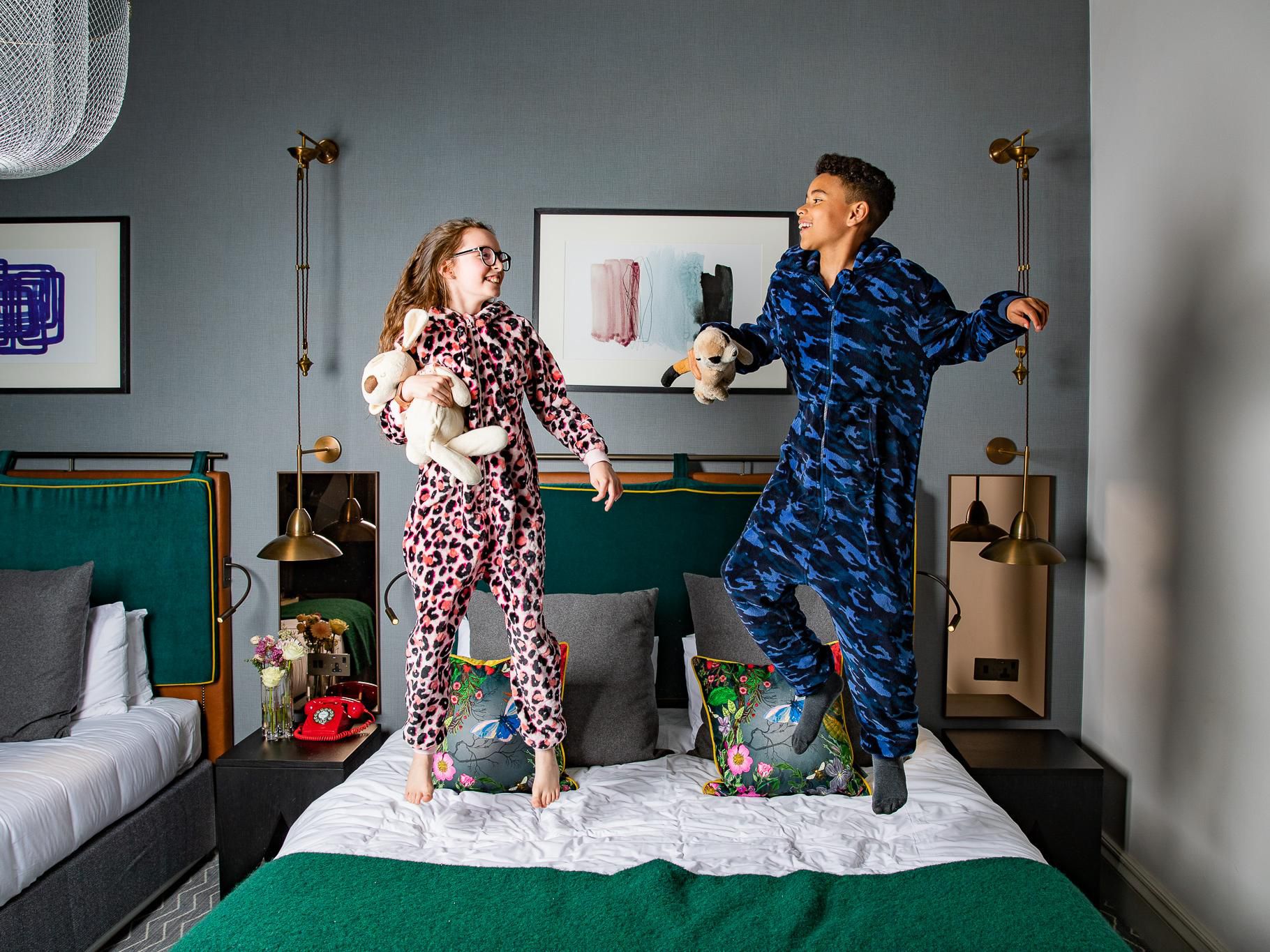 Kids jumping on bed in hotel guestroom
