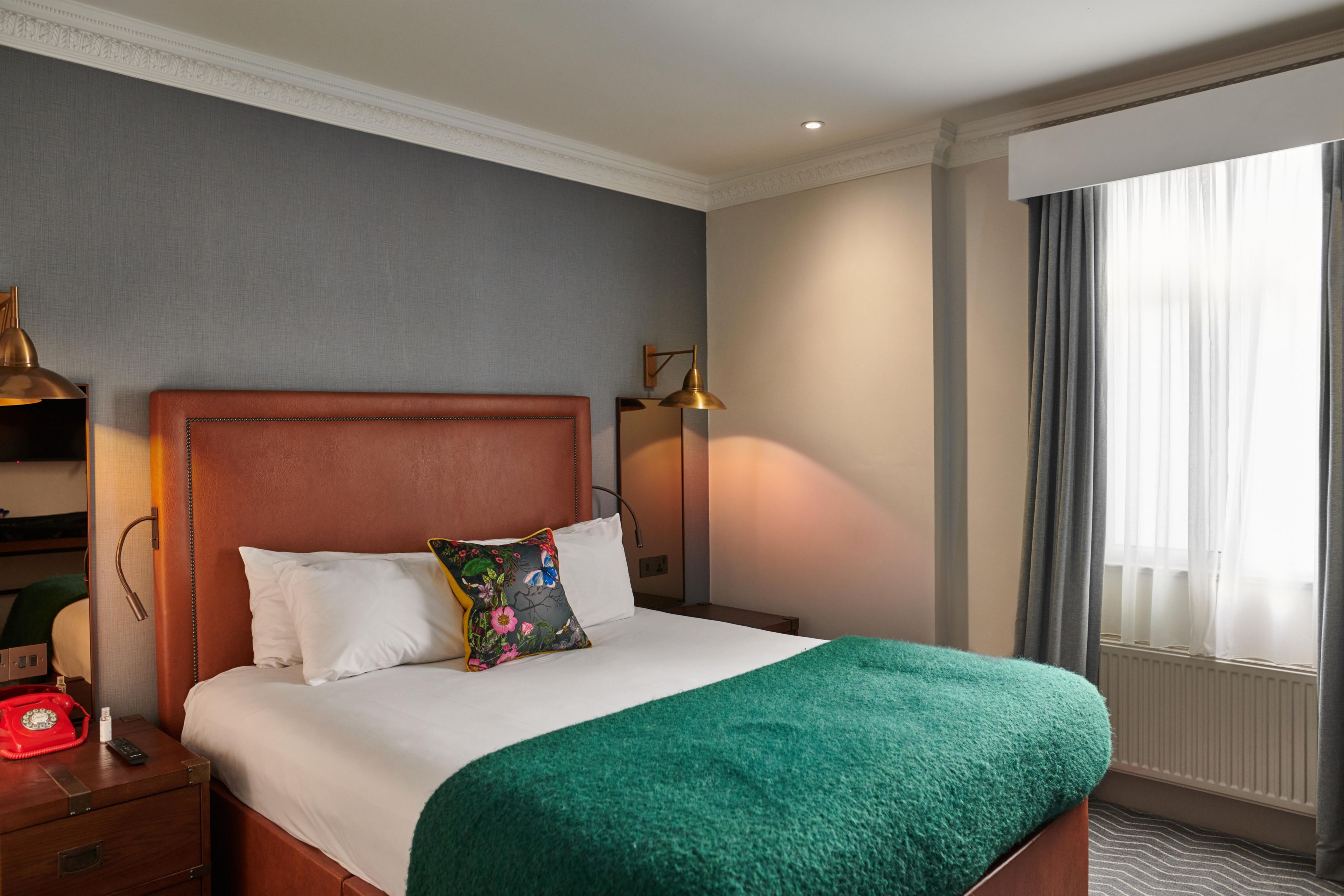 Double hotel guest hotel room with a green throw and bedside table