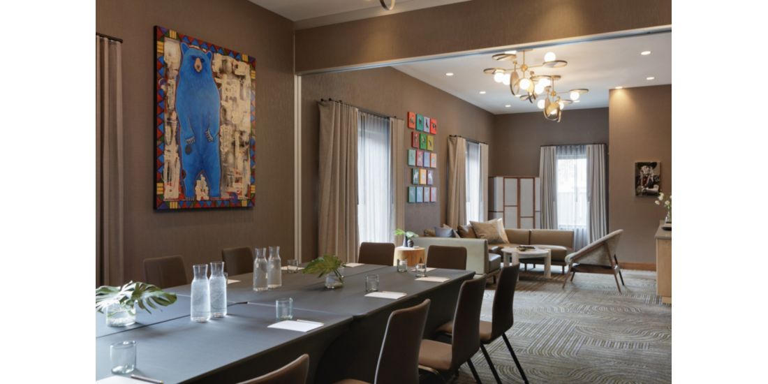 meeting space with a boardroom table, a section couch and colourful artwork