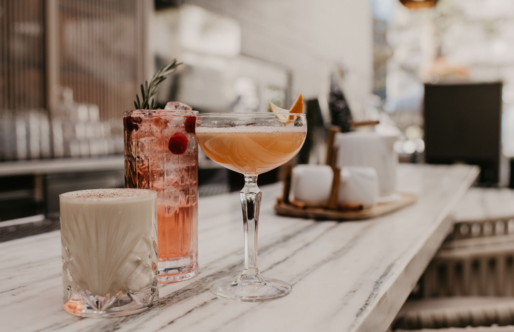Three beautiful cocktails with colourful garnishes on an outdoor bartop