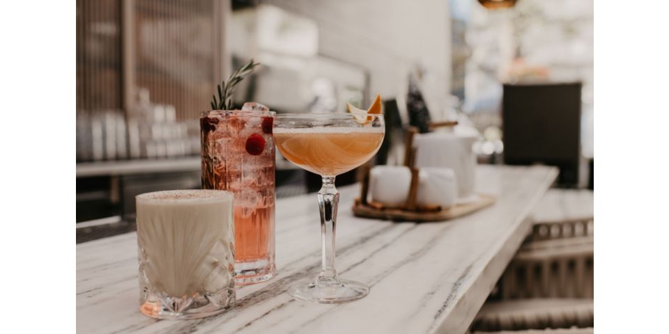 户外吧台上有三杯精美的鸡尾酒，配以五颜六色的装饰品