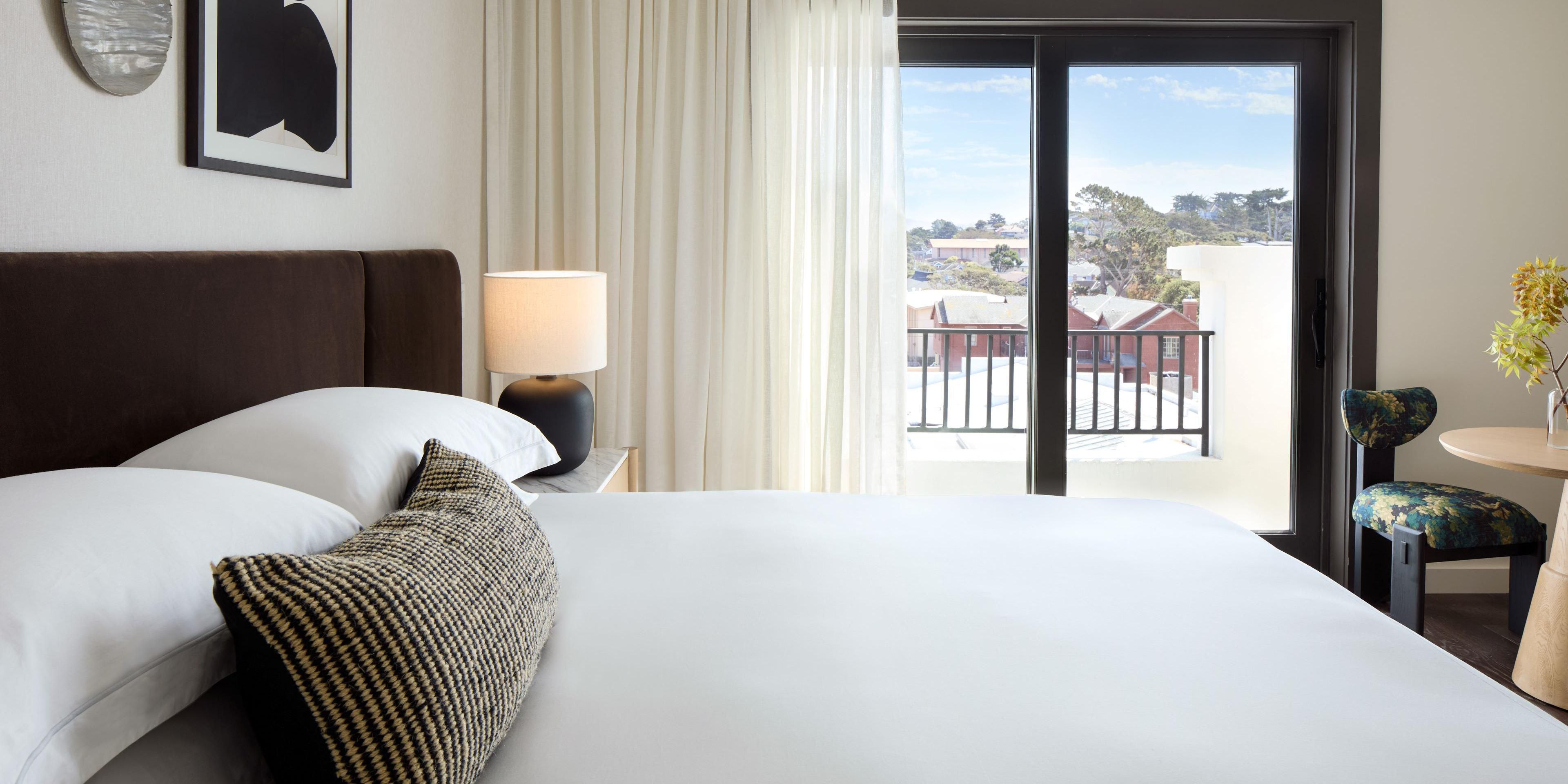 Elegant Pacific Grove guestroom with balcony and natural light.