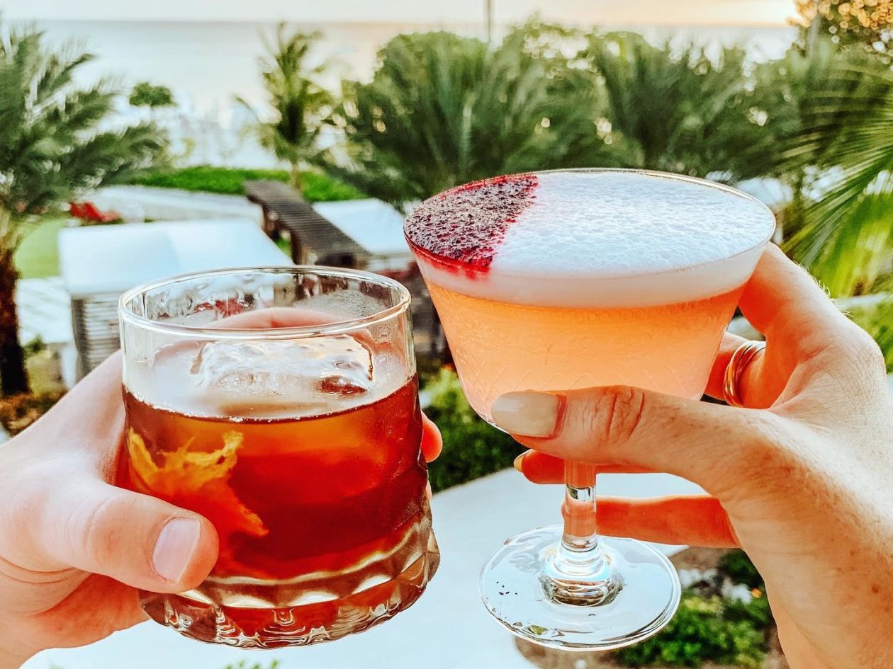 Two hands holding bar drinks