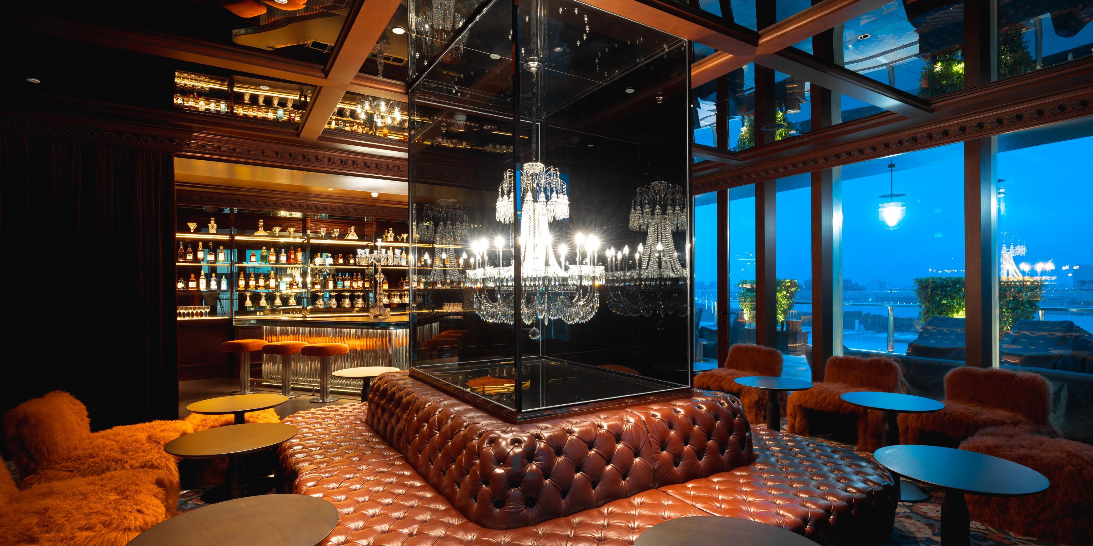 Gilded mirrors evoke a golden-age glamour, while crystal sconces cast a soft, starlit glow. The cabaret-inspired lounge sets a uniquely immersive scene, an ambiance that extends seamlessly to the outdoor terrace, offering sweeping views of the river and the boundless city beyond.