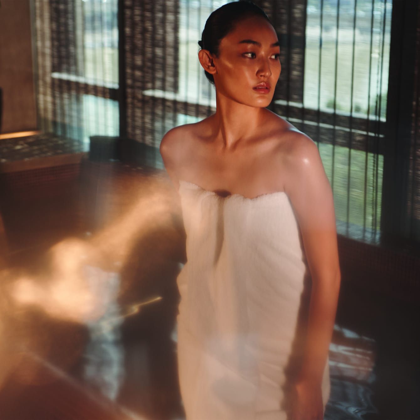 A woman in a steam chamber relaxing with an outdoor view.