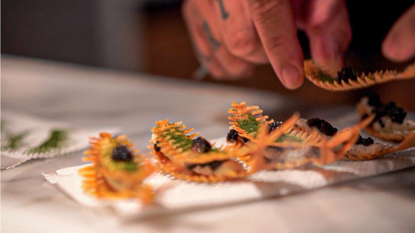 A Master Chef completing a delectable dish of small bites.