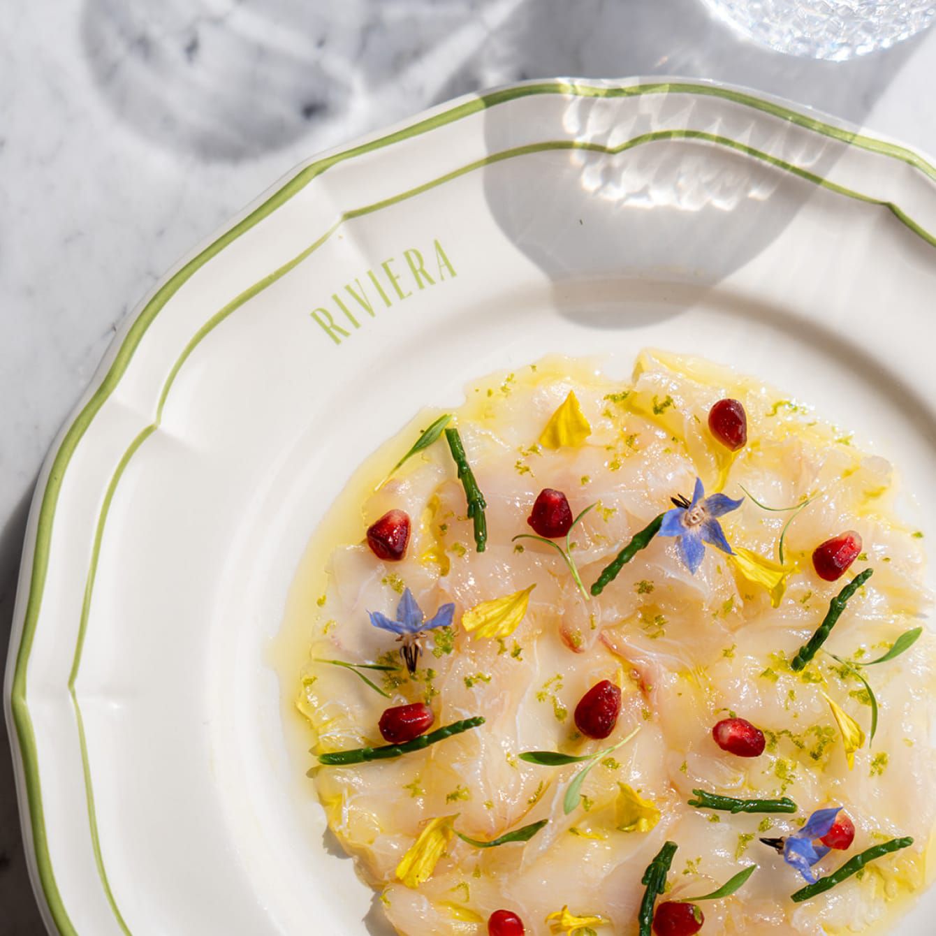 A masterpiece of scallop crudo dish garnished with local flowers.