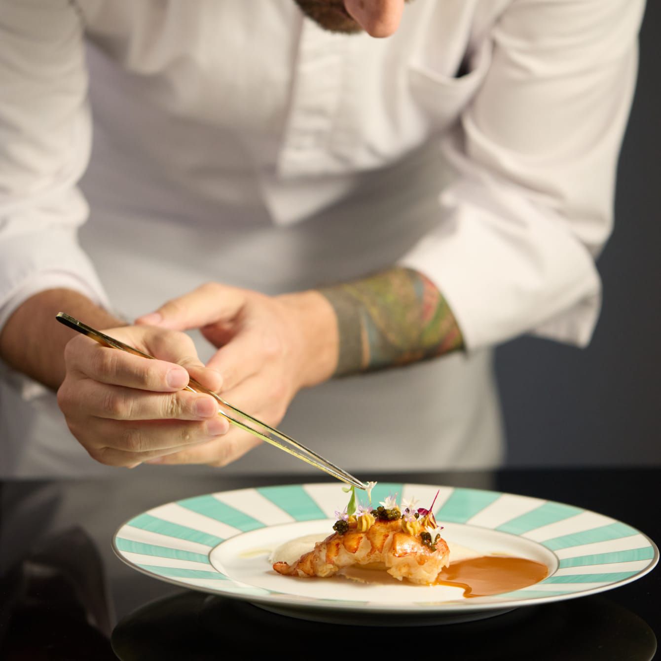 A sous chef putting the finishing touches on a main dish delicacy.