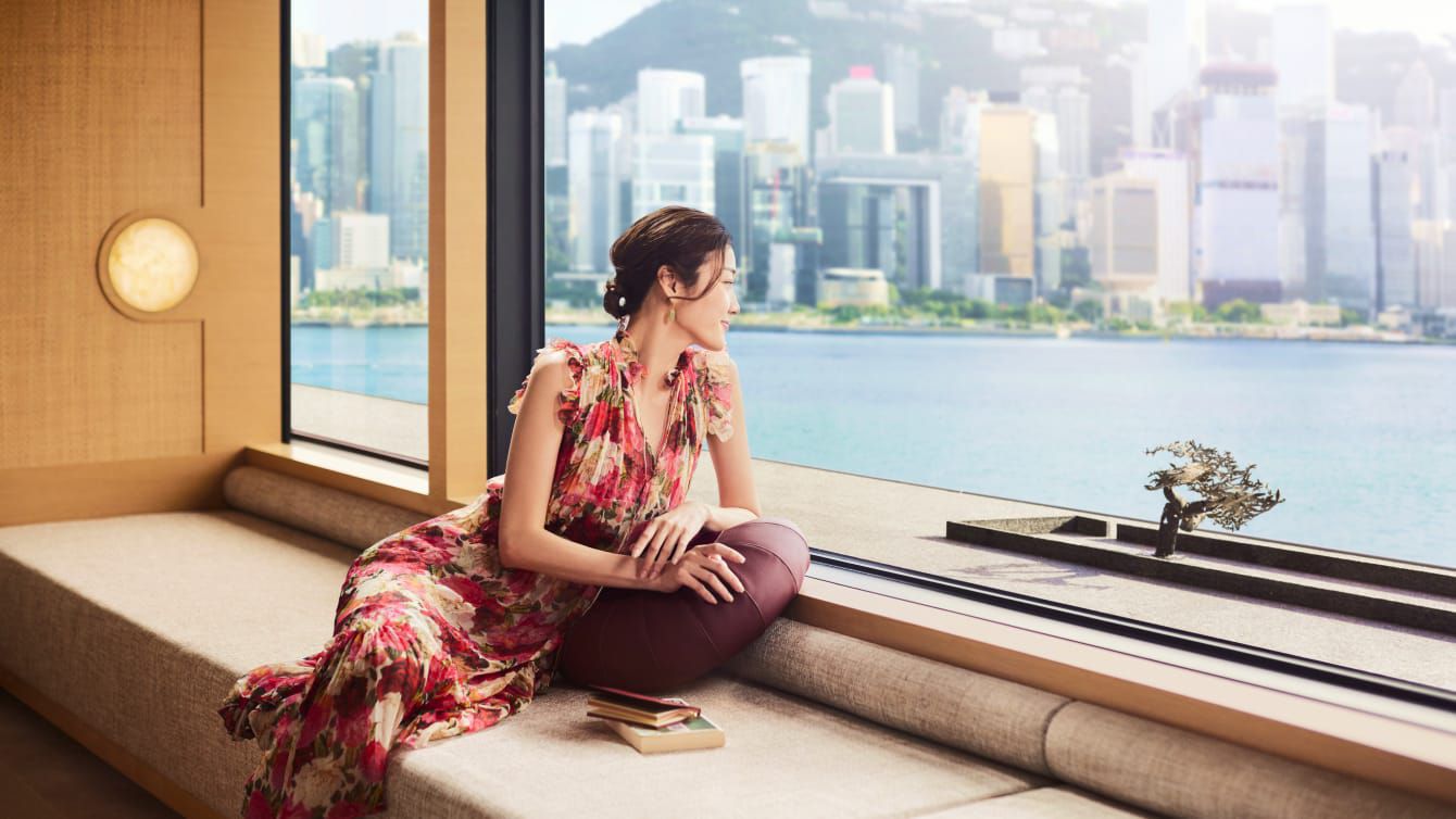 A beautiful young Asian woman enjoys the view of Victoria Harbour in Hong Kong.