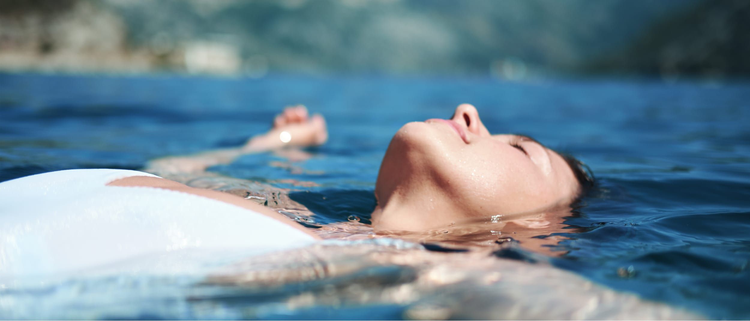 A woman floating in the sea in a state of bliss and relaxation.