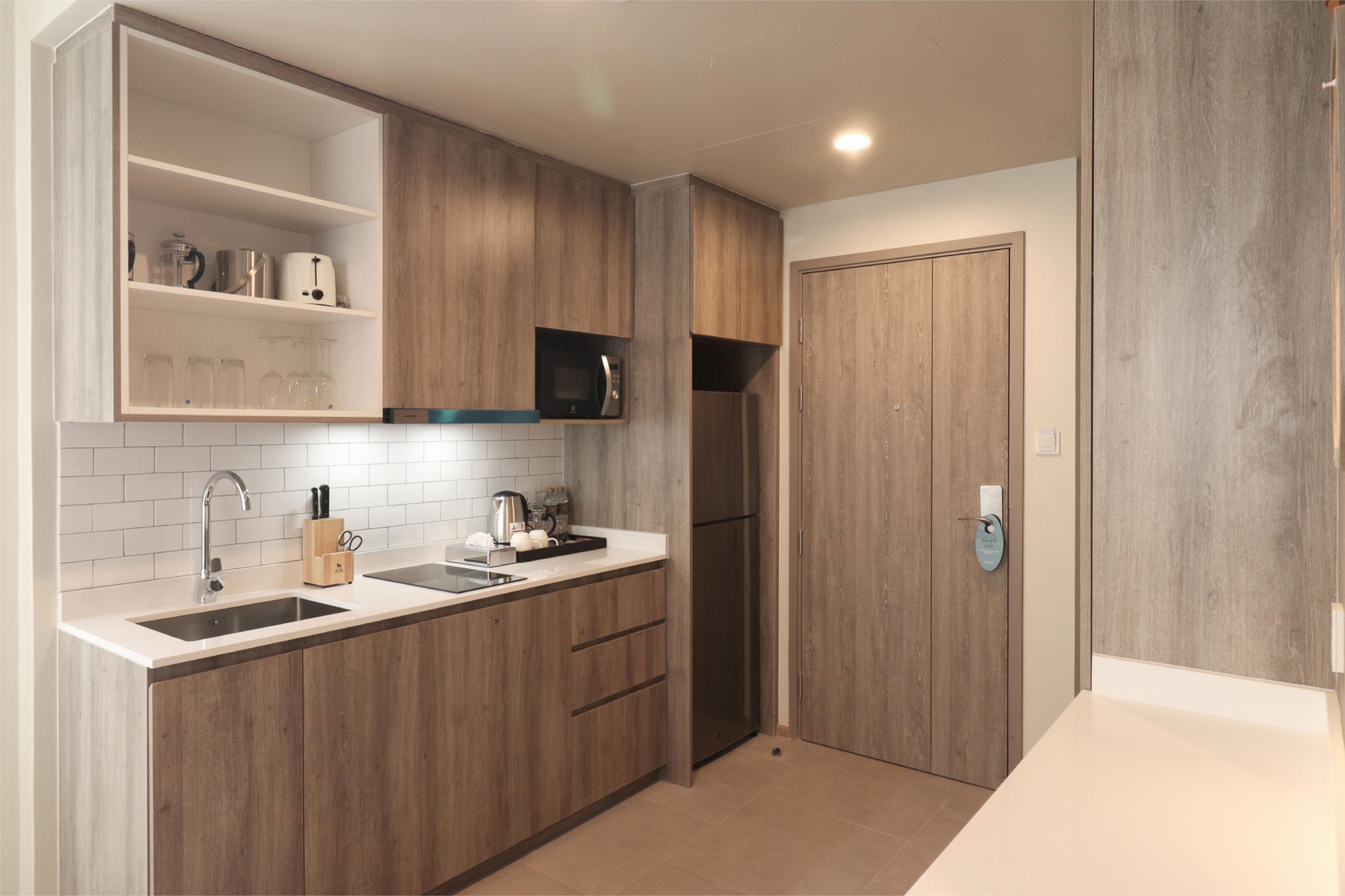 Each suite offers a separate living area with a plush sofa and a fully equipped kitchenette with a microwave, refrigerator, washing machine, and dryer. One and Two Bedroom Suites also have a private balcony with views of the vibrant Sukhumvit skyline, combining comfort and convenience in Bangkok.
