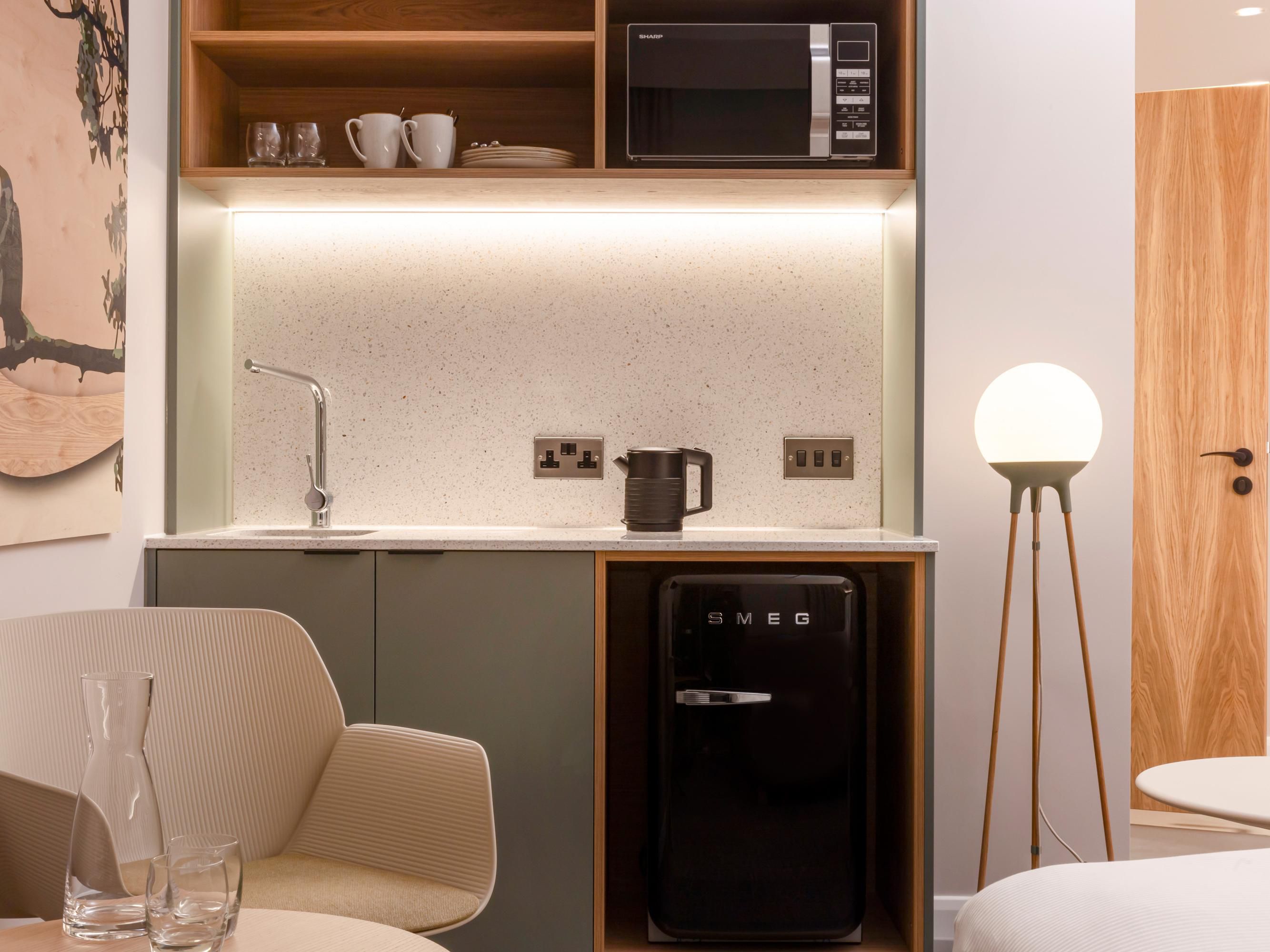 This stylish kitchenette room, complete with a single sofa bed, is perfect for guests planning a longer stay. The modern design includes a compact SMEG fridge, microwave, kettle, and ample shelving, allowing guests to enjoy home comforts. Comfortable seating and soft lighting create a comfy, functional space for both rest and productivity. 