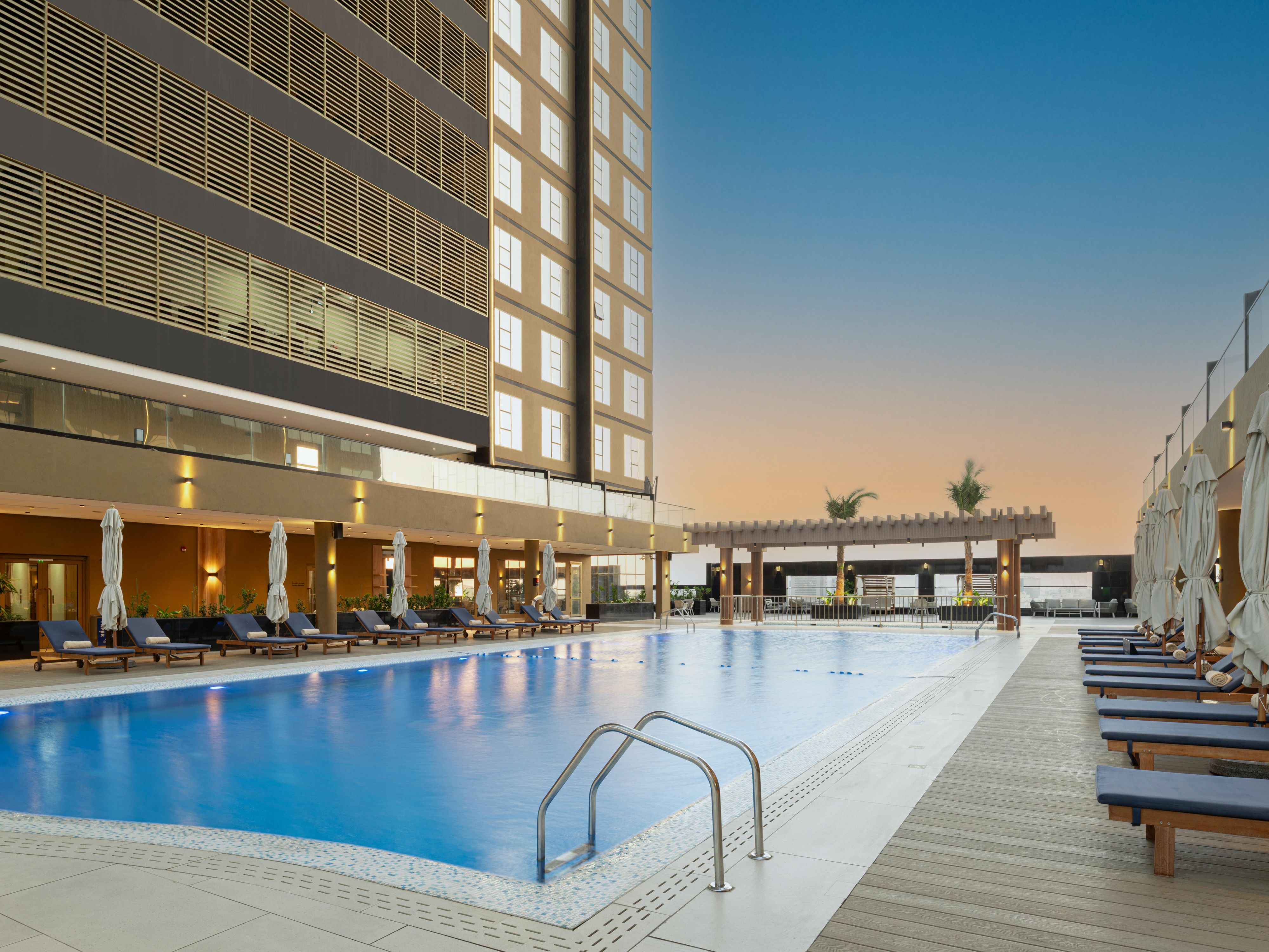 The outdoor swimming pool at voco Jeddah Gate offers a tranquil escape from the bustling city. Surrounded by lush greenery, the pool invites guests to relax and unwind. Whether you're seeking a refreshing dip or simply want to soak up the sun, this inviting space provides the perfect setting for a leisurely afternoon with comfortable loungers.
