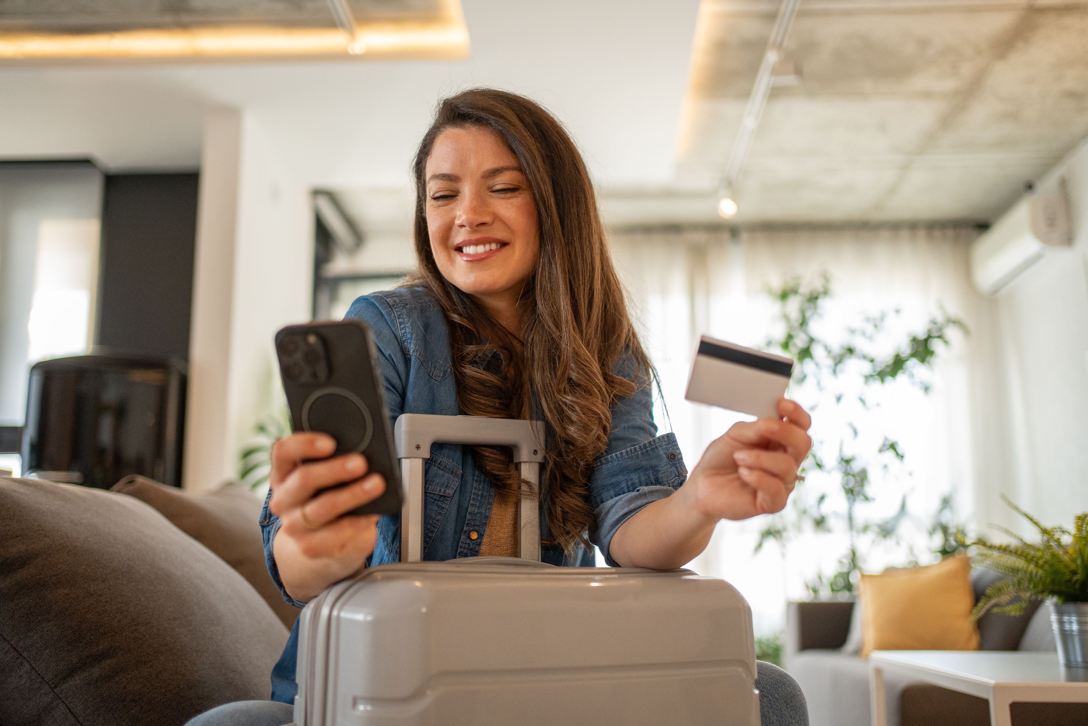 Woman at home booking a hotel trip on her phone.